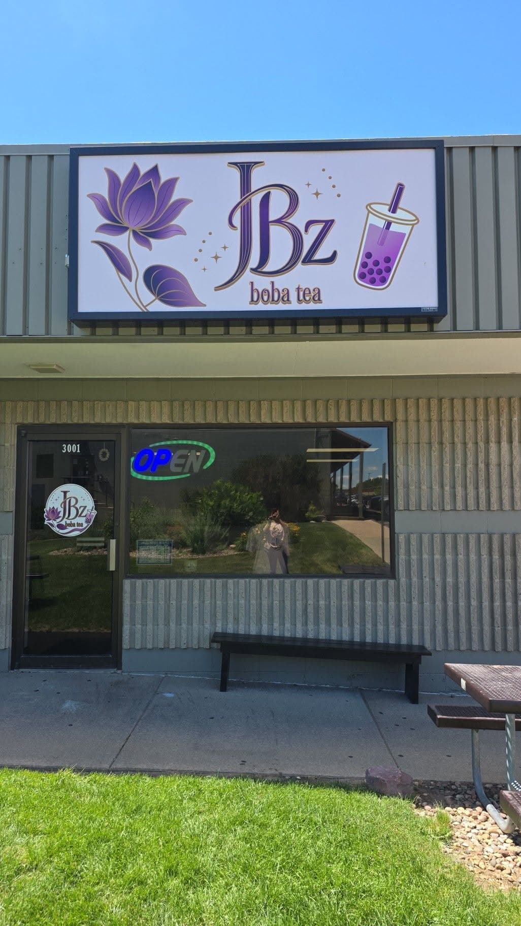The JBz storefront sign lit up at dusk