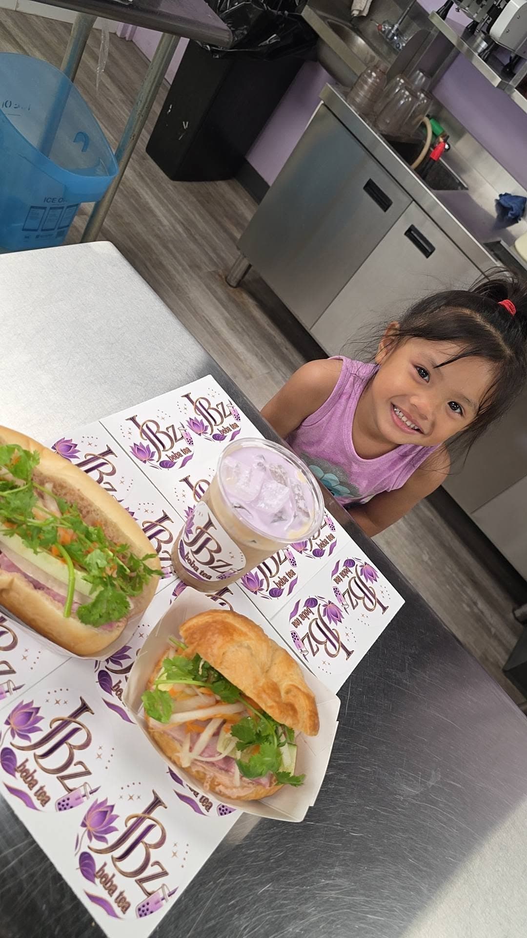 A happy kid at the JBz counter with banh mi and a drink, a family weekend at the shop