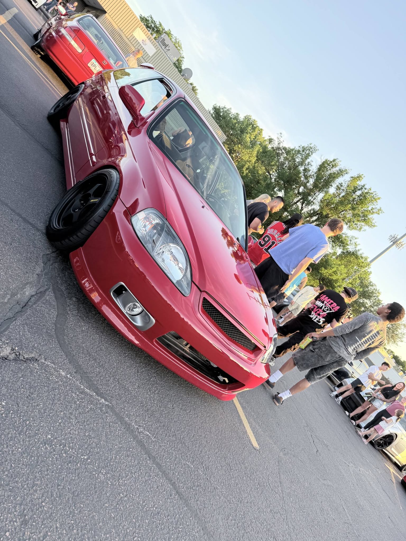 A crowd gathered around a red build at the meet