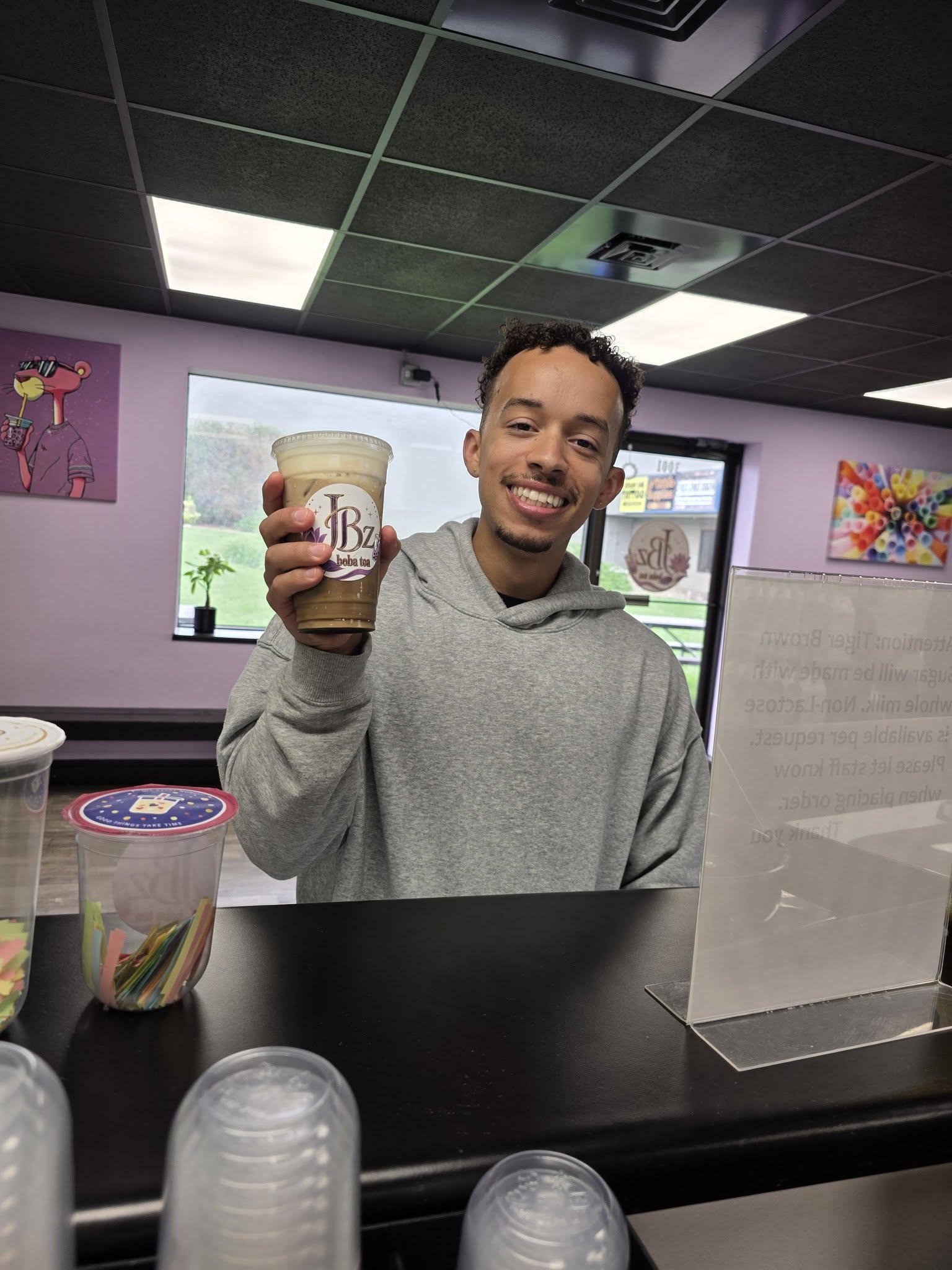 A hand holding up a freshly iced JBz fruit tea